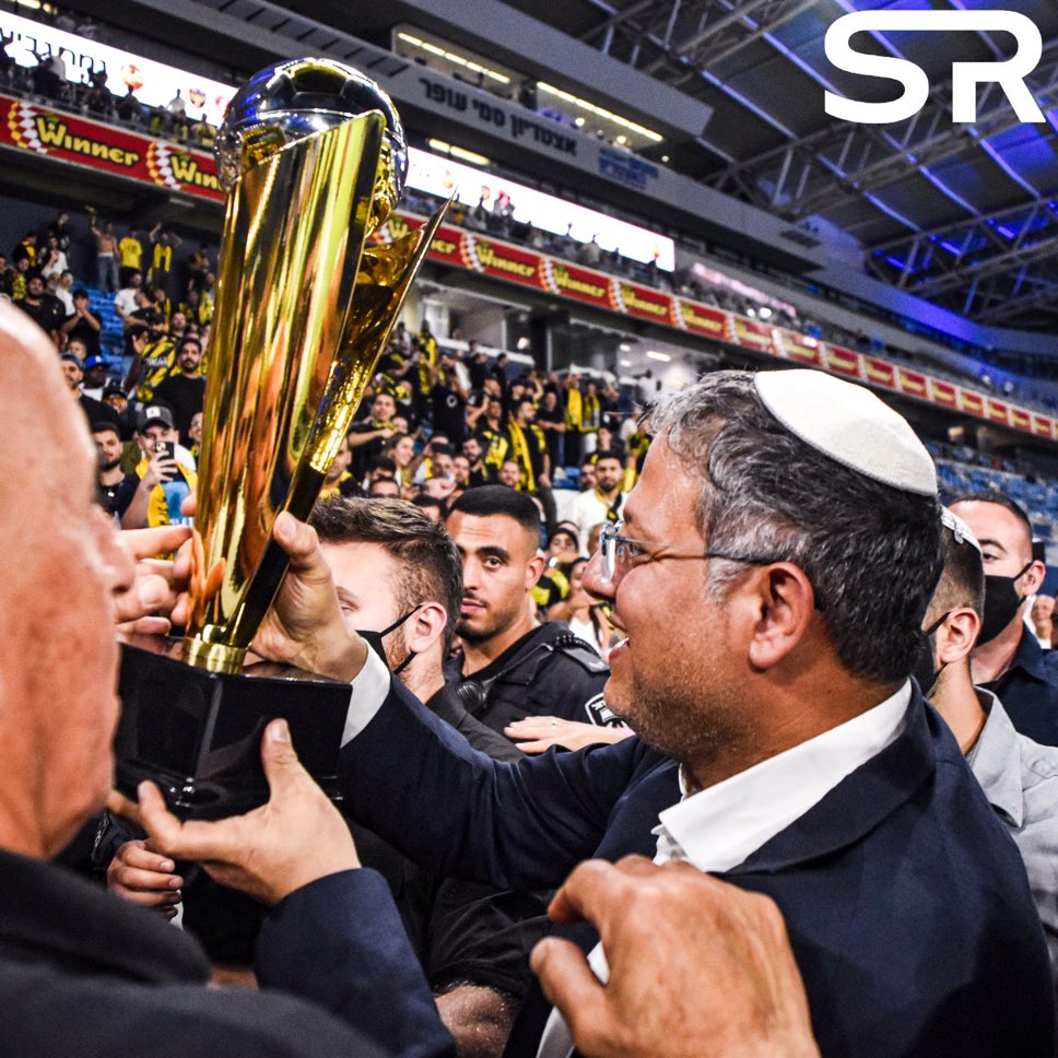 בתמונה: משהו מגוחך שאין לו ערך וחשיבות ולידו גביע הטוטו