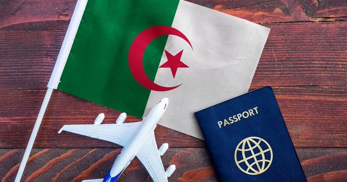 Wooden surface displays small Algerian flag with green and white stripes red star and crescent small French flag with blue white red vertical stripes white airplane model blue passport with world map emblem