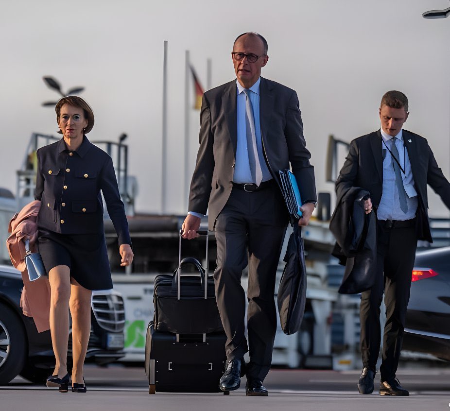 Le chancelier allemand en déplacement officiel. 

Il traîne sa valise et tient ses dossiers lui-même.
Il dirige est la 1ere économie européenne.