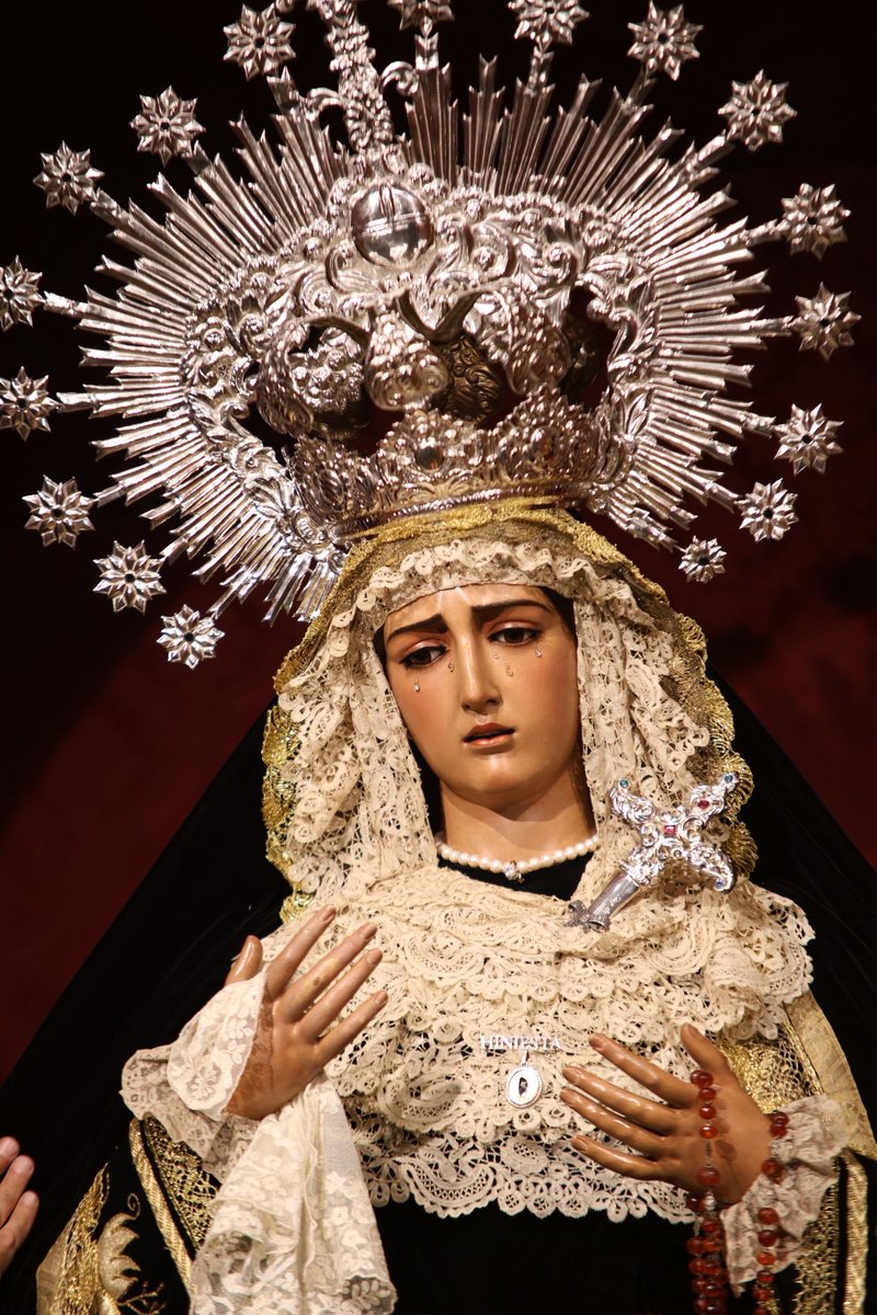 HdadHiniesta's tweet photo. 🖤 LA VIRGEN DE LA HINIESTA DOLOROSA EN EL MES DE LOS DIFUNTOS |

En este mes de los fieles difuntos, la Santísima Virgen de la Hiniesta Dolorosa viste su tradicional atuendo de luto, símbolo de oración y recuerdo por quienes ya gozan del descanso eterno.

Luce saya y manto de terciopelo negro. La saya, con apliques en oro con motivos florales y vegetales, fue realizada por NHD Joaquín Sánchez Blanco y NHD José María García Rodríguez en 1996. Ese mismo año, NHDoña Lorena Montero Rodríguez donó el manto, de terciopelo liso con galón dorado y forro morado. Sobre sus sienes, corona de metal plateado utilizada para su bendición en 1937. 

También luce broche relicario de Santa Ángela de la Cruz de plata sobredorada donado por un grupo de hermanos, broche de plata y nácar con relicario de María Santísima de la Hiniesta desaparecida en 1932 donado por NHD José Maria Ruiz Rueda, tocado de encaje duquesa estrenado en 2024 y donado por el grupo de priostía, broche con su nombre en plata y puñal de plata donado por NHD Emilio Balbuena Arriola en sus bodas de plata como hermano de la corporación. 
Como estreno, destacamos el rosario de ambar natural facetado y filigrana de plata del siglo XVIII donado por la familia Martín Jaén.

🕯️ Santísima Virgen de la Hiniesta Dolorosa, ruega por todos los fieles difuntos.

#SoydeLaHiniesta
#LaEstrellaSublime