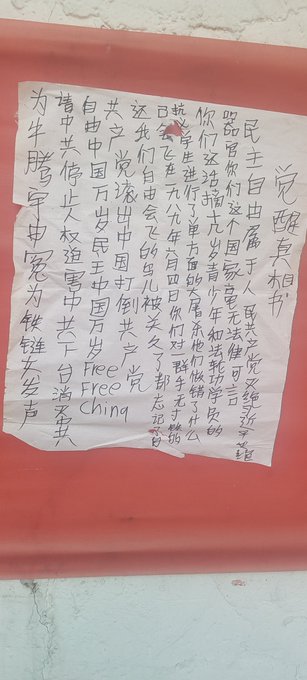First image shows a blue police station signboard with Chinese text including 报警 and 110 emergency number, a white paper notice pasted over it with handwritten Chinese characters protesting against CCP and calling for freedom, and a red phone attached to the wall. Second image displays a beige wall with a large white paper poster covered in dense handwritten Chinese text denouncing CCP tyranny, human rights abuses, and demanding release of political prisoners like Feng Yongjun. Third image features a red wall with a smaller white paper strip containing handwritten Chinese text criticizing CCP dictatorship and advocating for democracy and freedom. Fourth image depicts a white utility pole on a street with parked vehicles and scooters in the background, graffiti in black Chinese characters reading 法轮大法好真善忍 meaning Falun Dafa is good, truthfulness compassion forbearance.