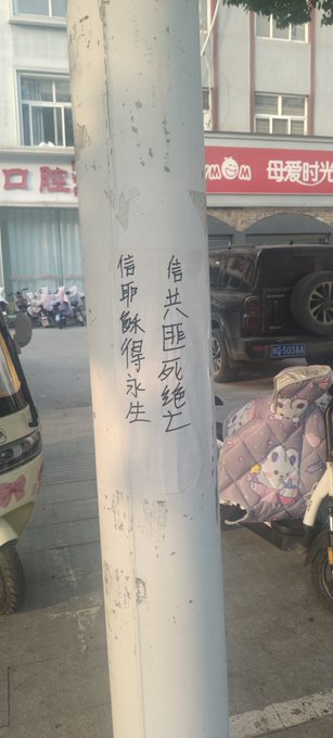 First image shows a blue police station signboard with Chinese text including 报警 and 110 emergency number, a white paper notice pasted over it with handwritten Chinese characters protesting against CCP and calling for freedom, and a red phone attached to the wall. Second image displays a beige wall with a large white paper poster covered in dense handwritten Chinese text denouncing CCP tyranny, human rights abuses, and demanding release of political prisoners like Feng Yongjun. Third image features a red wall with a smaller white paper strip containing handwritten Chinese text criticizing CCP dictatorship and advocating for democracy and freedom. Fourth image depicts a white utility pole on a street with parked vehicles and scooters in the background, graffiti in black Chinese characters reading 法轮大法好真善忍 meaning Falun Dafa is good, truthfulness compassion forbearance.