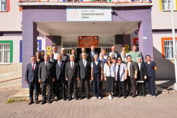 First image shows a group of adults in formal attire including men in suits and women in modest clothing standing around a young boy in a green uniform holding a letter in a classroom with Turkish flags posters and a whiteboard. Second image depicts a classroom full of young students in green uniforms sitting at desks with gifts and bags some holding items while several adults in suits stand at the front near a green board with decorations and Ataturk portrait. Third image features a large group of adults in business attire both men and women posing in front of a school building entrance with a sign reading ehit Mehmetik İlkokulu and colorful flags. Fourth image is a formal Turkish letter on official paper with seals signatures and text about education ministry activities.