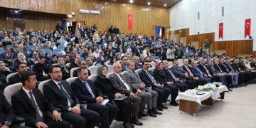 First image shows rows of attendees in formal attire seated in an auditorium with wooden walls Turkish flags and a table with flowers at the front. Second image depicts a woman in headscarf speaking at a podium with microphones and a university logo on the stand against a dark curtain backdrop. Third image features a man in suit at a podium with microphones in front of a screen displaying event title Calisma Yurdunda Din Ogrenimi Vizyonu Turkiye 31 Ekim-17:00 Saat 09:00-17:00 and logos. Fourth image displays a group of officials including men in suits and women in headscarves seated on stage with microphones and flowers in front of an audience.