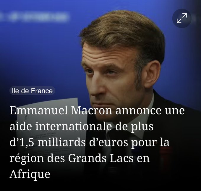 Emmanuel Macron, a middle-aged man with short brown hair and a serious expression, wears a dark suit and blue tie while seated and looking to the side in a formal setting. The background is blurred with blue tones. Overlaid white text in French reads Emmanuel Macron annonce une aide internationale de plus de 1.5 milliards deuros pour la region des Grands Lacs en Afrique. A small label Ile de France appears at the bottom.