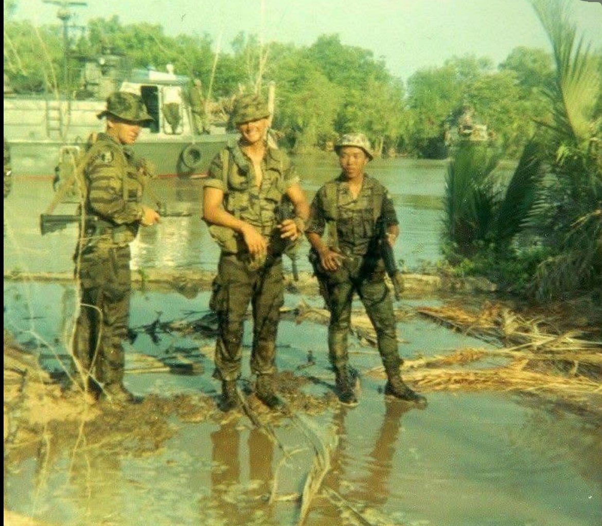 Csm John Henry Hess :
 “A-404 away from our airboats; in the : Ca Mau Peninsula, working with the U.S.Navy, as grunts. This is our medic Darrell Leach and I believe the team Sgt. Ed Trent also the interpreter little Phi. You'll notice in the background on the river