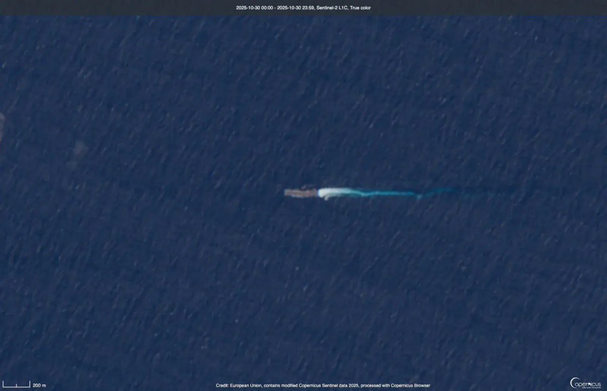 哥白尼哨兵 2 號的衛星圖像顯示深藍色的海洋表麵，一艘白色的大船位於中央，其後麵有一條長長的白色軌跡向右延伸。這艘船有一個矩形結構，似乎在部分多雲的天空下在平靜的水域中移動。左上角的時間戳顯示 2024 年 10 月 18 日 18：29：42 UTC。右下角包括哥白尼哨兵 2 號標誌和文字由歐洲航天局運營的哨兵 2 號衛星捕獲。