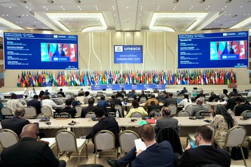 First image shows man in suit and tie standing at podium with UNESCO General Conference Samarkand 2025 sign behind him surrounded by numerous international flags including Turkish flag. Second image depicts three people two men and one woman in formal attire standing in front of blue wall with UNESCO General Conference Samarkand 2025 banner dated 30 October to 13 November. Third image features large screen displaying man speaking at podium with UNESCO logo and Samarkand 2023 banner in background along with rows of international flags and conference setup. Fourth image captures wide view of conference hall with multiple screens showing speakers long tables with delegates seated and array of international flags lining the walls.