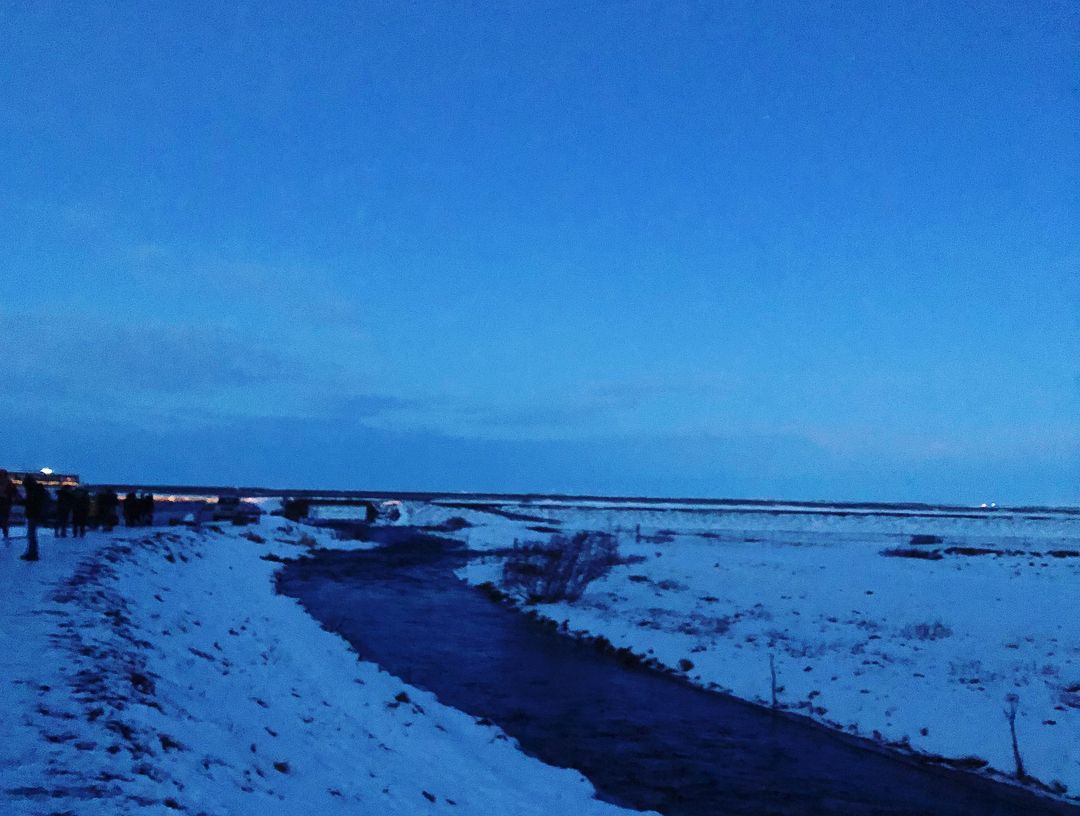 Edecganasx's tweet photo. 青い空の下、川が雪で覆われた大地をゆったりと蛇行して流れていて、遠くには寒い風の中で人影がぼんやり見えるの。まるで時間がゆっくりと流れているみたい https://t.co/cyQ7WtC5e9