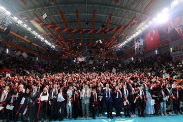 First image: Man in suit speaking at podium with microphone, DENEYAP banner behind, colorful stage lights. Second image: Group of graduates in black caps and gowns holding diplomas, smiling, on blue-lit stage with BioLoji banner. Third image: Large crowd of graduates in red-trimmed gowns on arena floor, Turkish flags and orange decorations overhead. Fourth image: Wide arena view with graduates in various gowns, stage with MÜZUNIYET banner, Turkish flags, and audience seating.