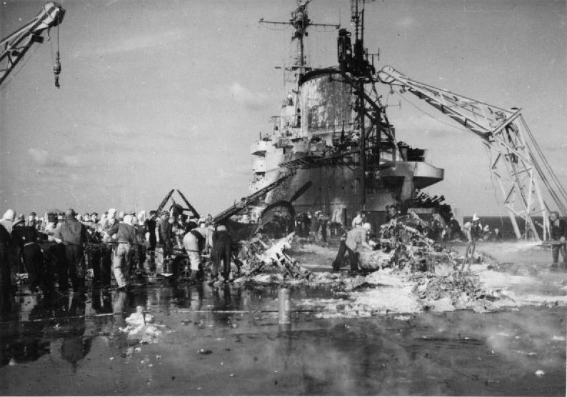 HMS Formidable crewmen starting to remove the wreckage of Japanese kamikaze aircraft from the flight deck, Pacific Ocean, 4 May 1945