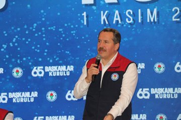 First image shows a man in a white shirt and red-and-navy vest holding a microphone while speaking on a stage with a blue backdrop featuring white text for 65. Presidents Council and Antalya 2025 along with rose emblems. Second image depicts a row of men in suits seated behind a long table on a stage with a large blue screen displaying 65 Presidents Council and Turkish flags flanked by flower arrangements. Third image captures a large group of men mostly in suits and vests standing together on a stage in front of a blue screen with the event title 65 Presidents Council Antalya 2025 and red banners. Fourth image presents a diverse group of about 30 people including men and women in formal attire such as suits and dresses posing in a row before a blue backdrop announcing 2025/2026 New Term Presidents with stage lighting.