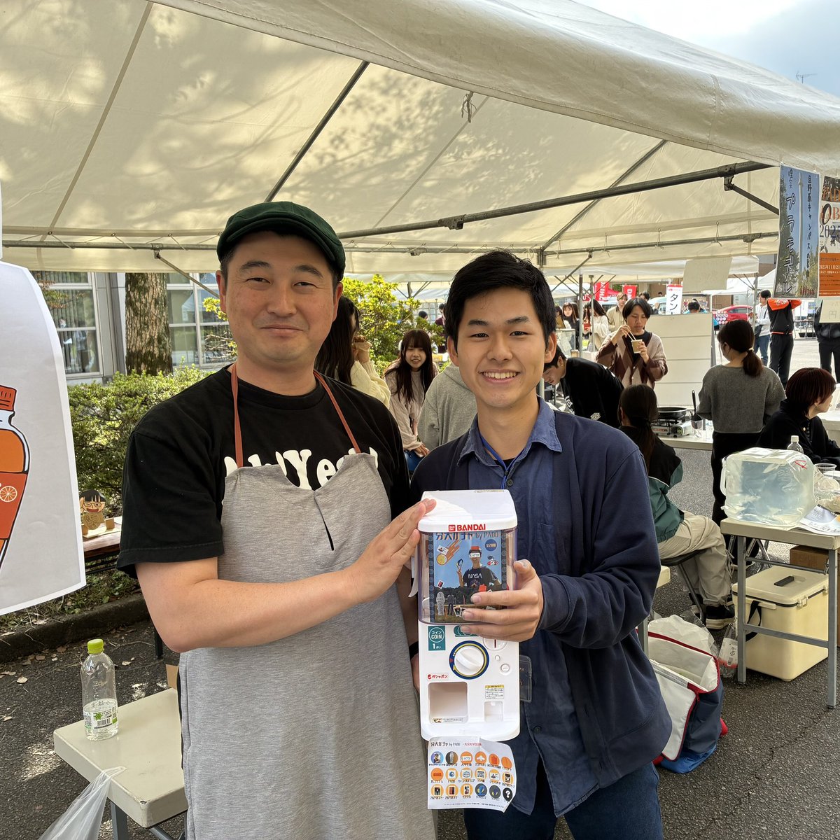 大分大学旦野原キャンパスの学園祭に来ました。サークル「BunDaiドリーム 」は、シャインマスカットフルーツあめと巨峰ソーダをご提供中です。おとなりの「PADOラボ」ブースで射的をしたら、部長さんに軽くヒットしてしまいました。お詫びのツーショットですが、笑顔です。