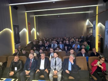 First image shows a man in a suit speaking at a podium with arms raised, wearing glasses, surrounded by red and white flower arrangements and banners reading TÜRKİYE KAMU-SEN and TÜRK BÜRO-SEN, with a blue screen in the background and another person partially visible nearby. Second image depicts a large audience of men and women in formal attire seated in a dimly lit hall with yellow lighting, wooden walls, a Turkish flag, and a banner on the side. Third image features four men in suits seated at a table on stage, one holding a microphone, with nameplates like BAŞKAN and name cards including BASAR VE BÜRO-SEN, against a screen displaying Türk Büro-Sen Istanbul 3 Nolu Sube Olağan Kongresine Hos Geldiniz. Fourth image shows a group of about 20 men in suits standing together in a hall with curved ceilings, yellow lighting, a Turkish flag, and a banner with a circular emblem.