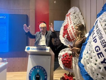 First image shows a man in a suit speaking at a podium with arms raised, wearing glasses, surrounded by red and white flower arrangements and banners reading TÜRKİYE KAMU-SEN and TÜRK BÜRO-SEN, with a blue screen in the background and another person partially visible nearby. Second image depicts a large audience of men and women in formal attire seated in a dimly lit hall with yellow lighting, wooden walls, a Turkish flag, and a banner on the side. Third image features four men in suits seated at a table on stage, one holding a microphone, with nameplates like BAŞKAN and name cards including BASAR VE BÜRO-SEN, against a screen displaying Türk Büro-Sen Istanbul 3 Nolu Sube Olağan Kongresine Hos Geldiniz. Fourth image shows a group of about 20 men in suits standing together in a hall with curved ceilings, yellow lighting, a Turkish flag, and a banner with a circular emblem.