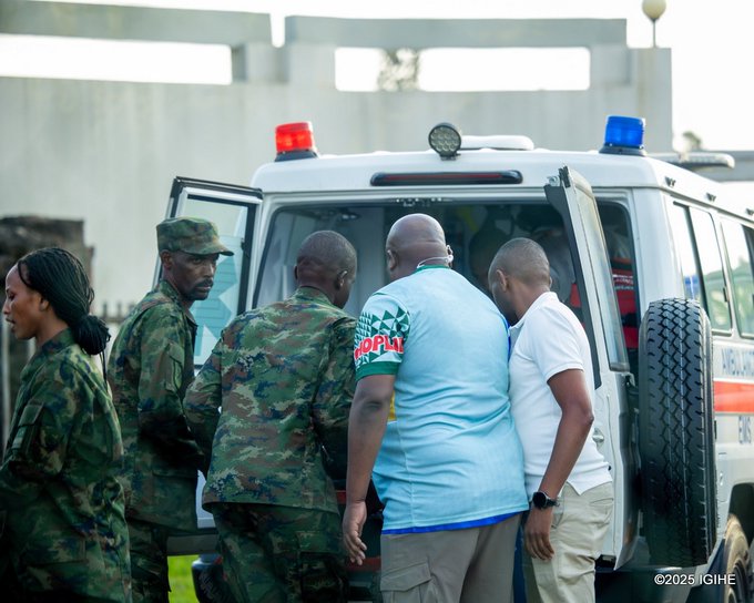 First image shows a male athlete in white and blue jersey with number 11, short curly hair, being embraced from behind by a teammate in blue jersey on green soccer field, with another player in yellow nearby, all appearing focused and supportive. Second image depicts several male athletes in blue and green uniforms assisting an injured player on stretcher, surrounded by medical staff in orange vests and caps, on a stadium field with crowd in background. Third image captures group of men including athletes in blue jerseys and military personnel in camouflage assisting injured player on red stretcher near white ambulance van with open doors. Fourth image shows emergency scene with ambulance van doors open, military personnel in camouflage and medical staff in orange vests loading injured individual, woman with braided hair assisting nearby.