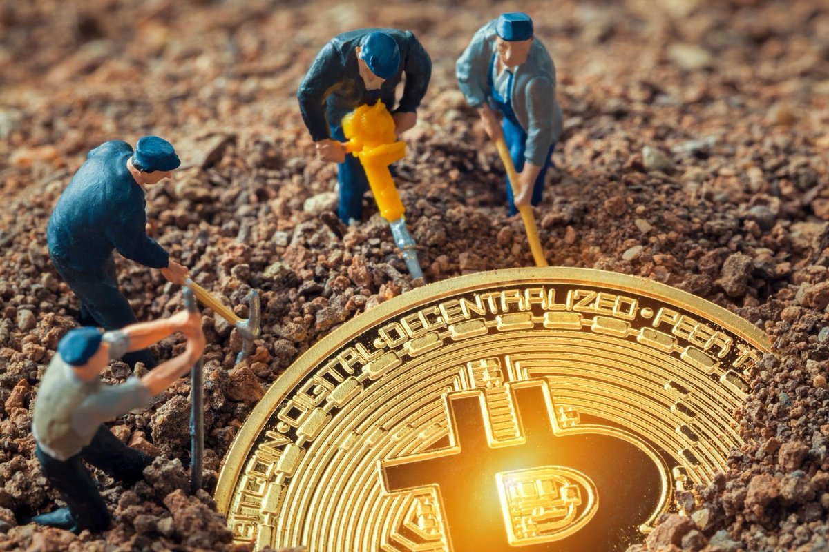 Miniature workers digging up a Bitcoin coin symbolizing crypto mining