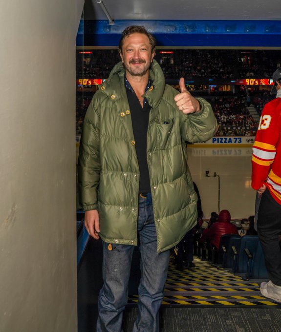 Ebon Moss-Bachrach smiles for a photo in a green jacket. 