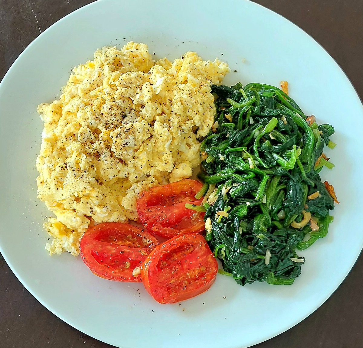 Late breakfast this morning after doing a bit of work in the garden. 
5 scrambled eggs with milk and butter, spinach boiled and fried with garlic, ginger in olive oil, and a nice ripe plum tomato. 
Very nice 🤌🤤😊