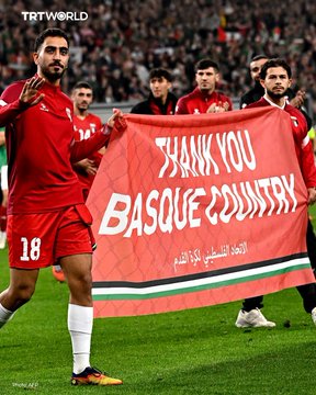 First image shows a male player in red jersey number 18 holding a large red banner reading Thank you Basque Country in English and Arabic with green white black red flag elements on a soccer field surrounded by stadium crowd. Second image depicts diverse crowd members holding green sashes reading Euskal Herria Palestina in Basque and Spanish with Palestinian flags visible in a stadium setting.