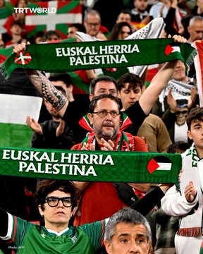 First image shows a male player in red jersey number 18 holding a large red banner reading Thank you Basque Country in English and Arabic with green white black red flag elements on a soccer field surrounded by stadium crowd. Second image depicts diverse crowd members holding green sashes reading Euskal Herria Palestina in Basque and Spanish with Palestinian flags visible in a stadium setting.