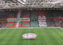 First image shows a large soccer stadium interior with a green field and circular center mark, surrounded by packed stands displaying a mosaic of green white red and orange flags forming patterns like crosses and stripes. Second image displays a stadium scoreboard reading 51 396 under Basque text for attendance, with illuminated sections and sponsor logos visible in the background. Third image captures the soccer field with players in red and green uniforms gathered near the center circle, referees in black, and stadium seating with green and red elements in the stands. Fourth image depicts a crowded urban street at dusk with historic buildings, a large group of people holding Palestinian flags, some wearing green hats, and others in casual attire waving banners.
