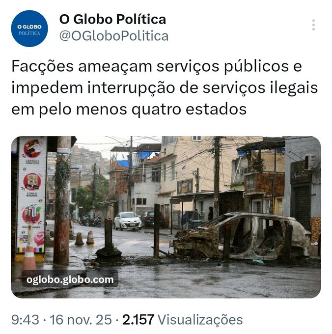 Screenshot of a news article from O Globo Política with headline about criminal factions threatening public services and preventing interruption of illegal services in at least four states, including publication details and view count, below which is a color photograph of a narrow urban street in a Brazilian neighborhood showing several multi-story buildings with laundry hanging, utility poles with wires, political posters on walls, a white car parked, and a severely burned and damaged vehicle with charred frame and debris scattered around, under overcast sky.