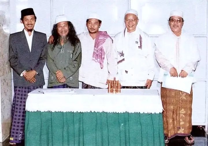 عَيْنِي إِلَى مُعَلِّمِي تَبْقَى بِكُلِّ جَلَالٍ
فَهُوَ السِّرَاجُ الَّذِي يُضِيءُ لِي فِي اللَّيَالِي

“Mataku memandang guruku penuh keagungan,
dialah pelita yang menerangi malam-malamku.”