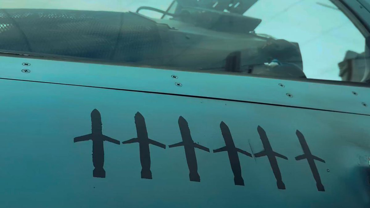First image displays the blue fuselage of a Mirage 2000 jet featuring six black silhouette markings of bombs indicating successful strikes. Second image shows a pilot in gray flight suit and helmet standing with arms crossed viewing the open cockpit of the Mirage 2000 on a runway with Ukrainian flag colors on the tail under cloudy weather.