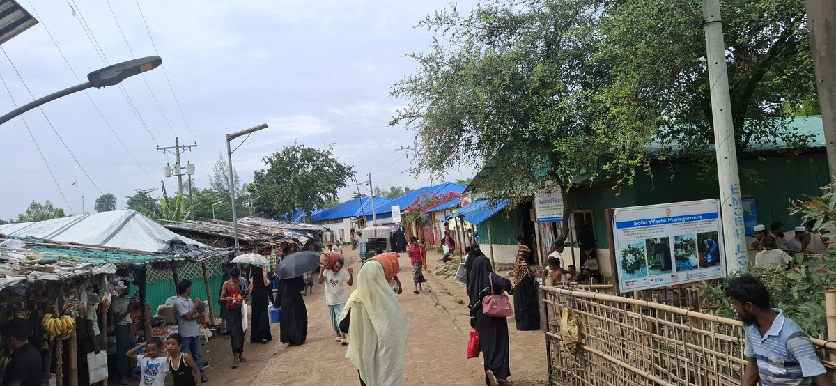 tg_azimullah's tweet photo. A crowded road winds through Camp-22, bustling with people. Some carry LPG cylinders, others fetch water, while children weave between them. The scene reflects the rhythm of survival — busy, determined, and full of life.

#Camp-22 #Rohingyarefugees https://t.co/PLJULgDwmF