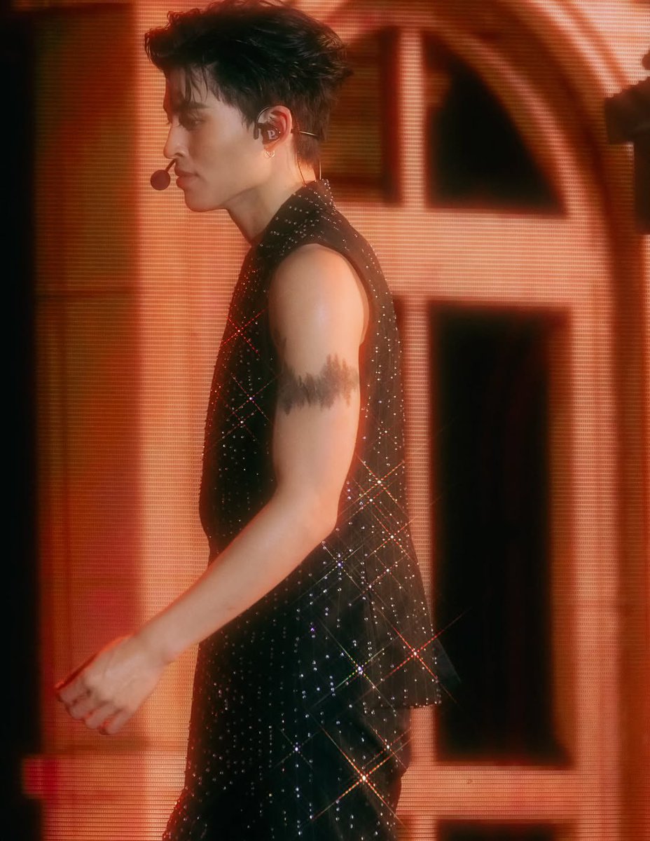 He stood beneath the chandelier of stars, his voice carving light into the dark, every note a thread weaving dreams into the air, soft enough to make silence listen.