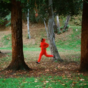 First image depicts a person wearing a full red tracksuit and black shoes running dynamically through a forested park setting with tall trees, green grass, and fallen leaves on the ground, captured in motion blur to emphasize movement. Second image is an album cover artwork in red and black tones featuring the circular text SCRAM prominently at the center, artist name DOMO GENESIS GRAYMATTER below it, a tracklist including Shedding Weight Make It Rain Money Good Gracious Clock Face featuring Swae Lee Nacho and Just Sweat No Tears, with credits to Plainface Kurt Rambis Money Alliknow Blue Slim Nacho and label Things Happen Records 2025.