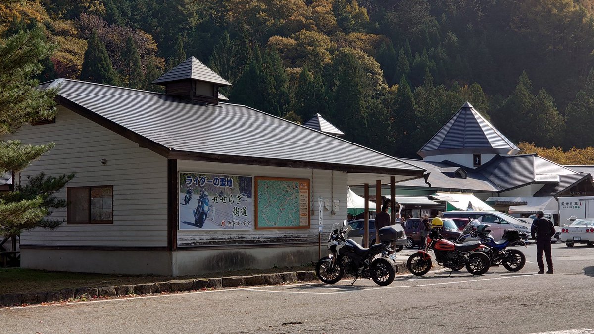 PCM8's tweet image. 秋の陽ざしがやわらかくて、エンジン音まで澄んで聞こえる。
ここは道の駅パスカル清見、ライダーたちの集まる峠のオアシス🏍️🍂
木造の屋根の向こうに広がるのは、金と朱のグラデーション。
一本の紅葉が空の青に映えて、まるで季節そのものが写真に写り込んだみたい。…