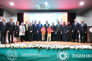 First image shows a family including a man in a suit, a woman in black attire, and two young children in orange school uniforms with backpacks standing at the entrance of Can Gür İlkokulu school building decorated with red balloons and flowers. Second image depicts officials including a man in a blue suit and a woman in orange at a signing table with microphones, Turkish flags, and portraits of Mustafa Kemal Atatürk and Recep Tayyip Erdoğan in the background during a protocol event. Third image features a large group of suited men and women, some in headscarves, with two children in orange uniforms posing on a stage with green banners reading T.C. Millî Eğitim Bakanlığı and TOGEM-DER. Fourth image shows numerous people seated around a white table in a meeting room with windows, plants, and a clock, including women in various attire like headscarves and suits, engaged in discussion.