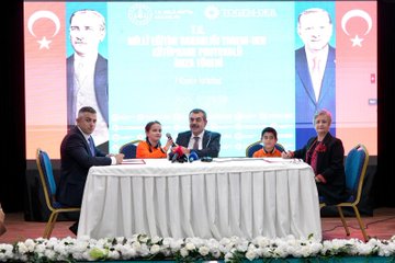 First image shows a family including a man in a suit, a woman in black attire, and two young children in orange school uniforms with backpacks standing at the entrance of Can Gür İlkokulu school building decorated with red balloons and flowers. Second image depicts officials including a man in a blue suit and a woman in orange at a signing table with microphones, Turkish flags, and portraits of Mustafa Kemal Atatürk and Recep Tayyip Erdoğan in the background during a protocol event. Third image features a large group of suited men and women, some in headscarves, with two children in orange uniforms posing on a stage with green banners reading T.C. Millî Eğitim Bakanlığı and TOGEM-DER. Fourth image shows numerous people seated around a white table in a meeting room with windows, plants, and a clock, including women in various attire like headscarves and suits, engaged in discussion.