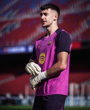 A young man with short dark hair and a focused expression stands on a green soccer field wearing a pink and navy sleeveless Barcelona FC goalkeeper jersey with the club crest, black shorts, and white goalkeeper gloves. The background features red stadium seating partially filled with spectators under a clear sky. In the second image, the same man dynamically reaches upward with both gloved hands to catch a bright yellow soccer ball marked with sponsor logos, his body extended in motion while wearing the same pink and navy uniform on the field with blurred stadium stands.