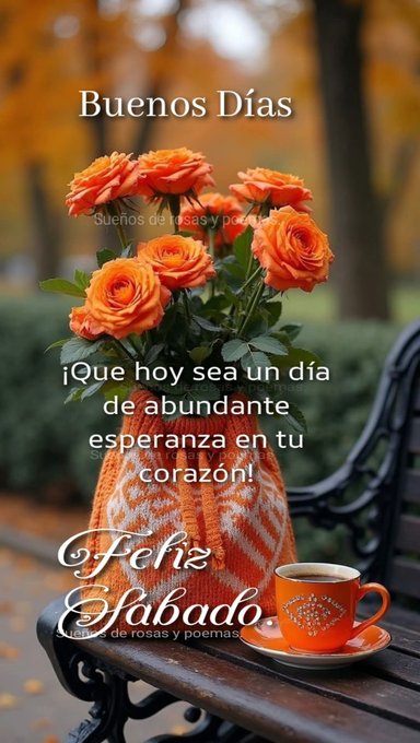 A bouquet of vibrant orange roses arranged in a colorful knitted vase sits on a wooden bench in an outdoor setting with blurred autumn foliage and trees in the background. Next to the vase is an orange ceramic cup and saucer placed on the bench. The scene conveys a peaceful morning atmosphere with warm tones.