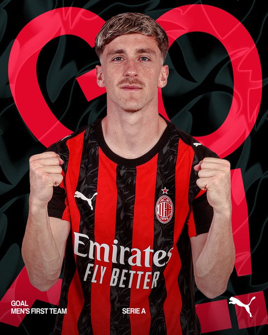 A young male athlete with light brown hair and a mustache stands in a dynamic pose with fists clenched smiling confidently wearing a red and black striped short-sleeved soccer jersey with Puma logo AC Milan crest and Emirates Fly Better sponsor text on the front posed against a dark background with red heart shapes.