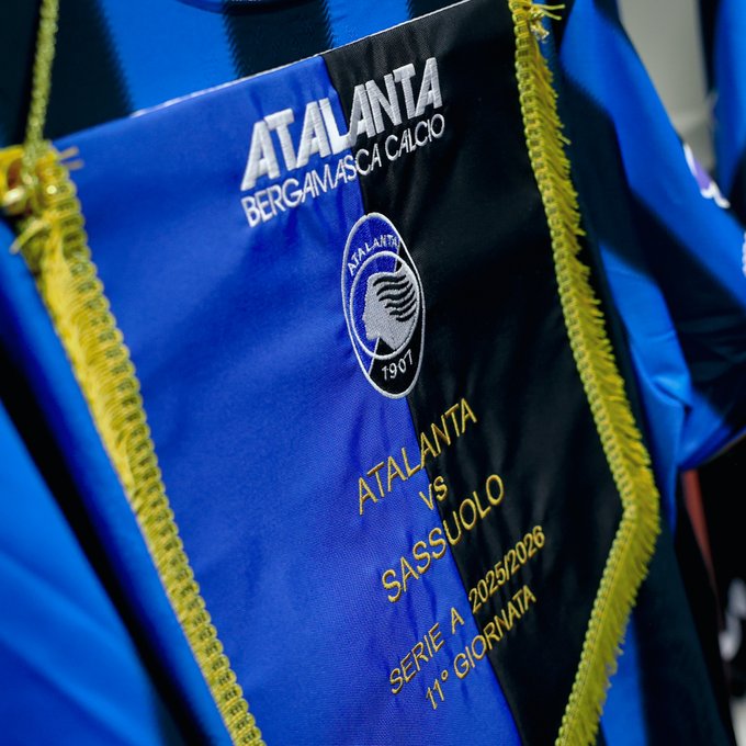 Blue and black banner displays Atalanta Bergamasca Calcio logo with a lion emblem and 1907 date on the left side, Sassuolo team name and emblem on the right, central text Atalanta vs Sassuolo above Serie A branding and 2025/2026 season 11th matchday details, gold fringes along edges.