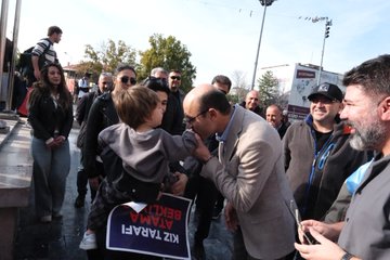 Group of people holding banners and Turkish flags in front of a tall statue of a man on horseback atop a pedestal surrounded by urban buildings under a clear sky. Banners in Turkish text demand equal rights and additional teacher appointments with numbers like 76 branches. Another image shows a bald man in suit shaking hands with a young boy holding a blue banner saying KIZILAY ATAMA with crowd around. Third image displays multiple protesters with various Turkish banners about teacher demands and union support in front of a monument. Fourth image features men and women in formal attire speaking to media with microphones near red banners and Turkish flags against a city backdrop.