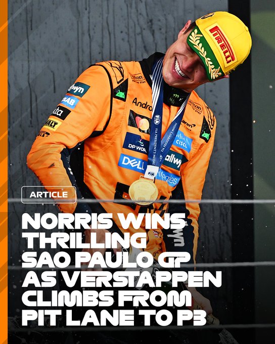 Lando Norris stands on podium in orange McLaren racing suit with sponsor logos including Dell and Andretti on sleeves and chest. He wears yellow Pirelli helmet with green accents and holds gold trophy. Blue medal hangs around neck. Background shows blurred crowd and fencing. Text overlay reads Norris wins thrilling Sao Paulo GP Verstappen climbs lane from P3.