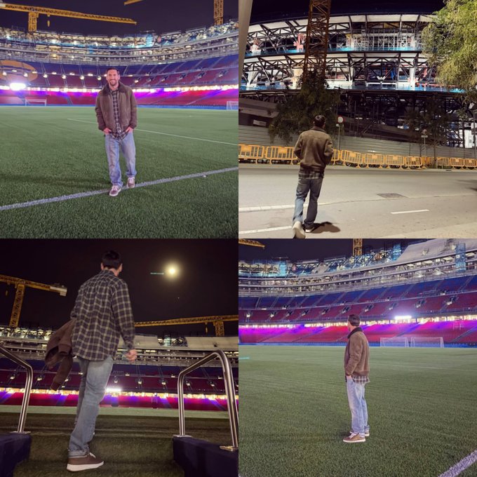 Four-panel collage of nighttime photos at Camp Nou stadium. First panel shows a person in a maroon jacket and jeans standing on the green field facing forward, with stadium seating, colorful lights, and construction cranes in the background. Second panel depicts the same person from behind, walking on the field with stadium structure and trees visible. Third panel features the person from the side, carrying a bag near railings with moonlight and stadium lights illuminating the area. Fourth panel shows the person standing near barriers on the field, with the stadiums blue and red seating and field lines prominent.