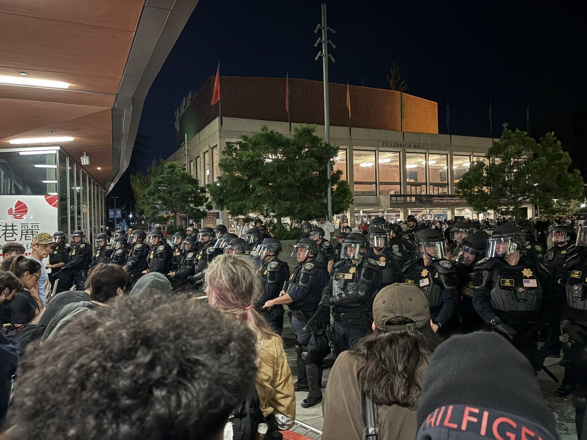 chrissaolson's tweet photo. Big crowd outside the TPUSA event at UC Berkeley right now. Protestors are chanting as cops are lined up with batons. https://t.co/YBQQcjqe7J