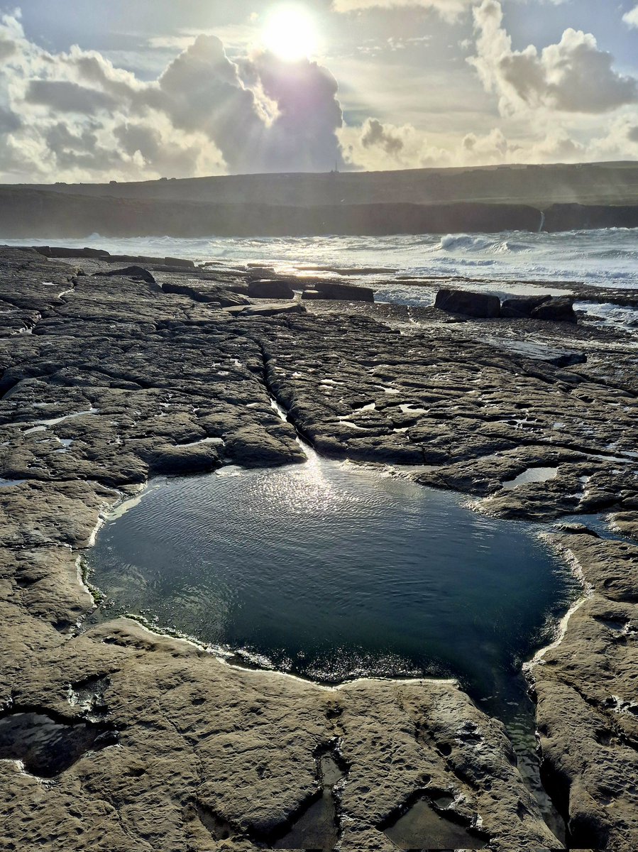 The rockpools calmness contrasts with the drama of the sea and sky behind it. 
County Clare, Ireland.