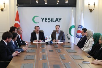 First image shows two men in suits sitting at a table with Turkish flags, Yeşilay logo on wall, documents and microphones present, one man signing a paper. Second image depicts a group of eight people including men and women some in hijabs around a long table with Turkish, EU, and Yeşilay flags, documents and water glasses on table. Third image features two men in suits holding signed documents with flags including Turkish, Yeşilay, and international organization banners in background. Fourth image shows a group of eight people standing around a long table with Yeşilay logo, Turkish flag, and other banners, individuals in formal attire including suits and hijabs.