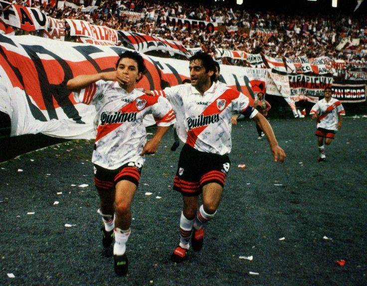 Andres_Burgo's tweet image. El hoy cumpleañero Enzo Francescoli abraza a Gallardo tras un gol del Muñeco a Independiente en 1997. Atrás, Berti. Más postales de época: pista de &quot;atletismo&quot; con piedritas y la bandera de &quot;River es el país&quot;. Rumbo al tricampeonato.