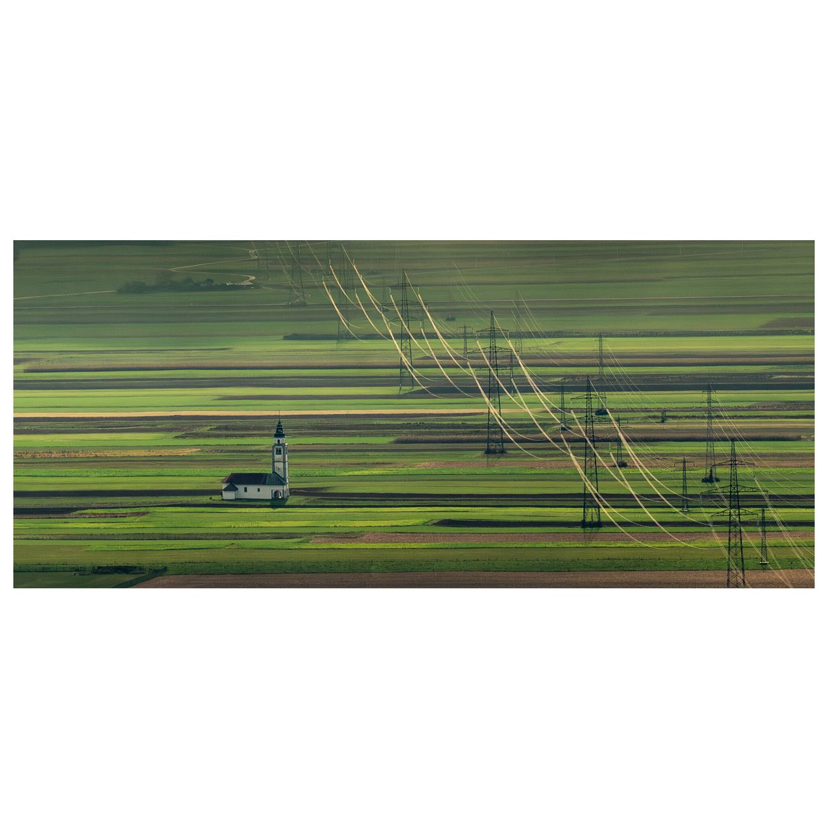 I love this shot taken a few weeks ago in #Slovenia. We travelled to a high viewpoint, it was a bit misty &amp; the sunlight catching the cables creates an interesting effect. I especially love the church nestled between the striped fields. Join me next year: phototours.in/slovenia