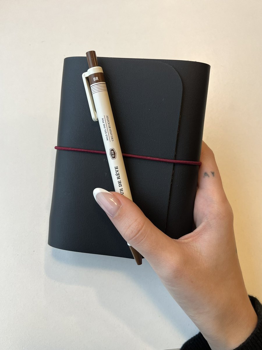 Un cuaderno de viaje tamaño pasaporte con sus respectivos cuadernos interiores a modo de agenda y notas para reseñas, y un boli de tinta marrón. Qué feliz me hace la papelería efectiva.