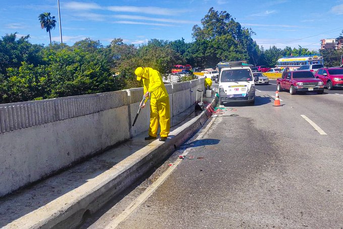 First image shows two workers in yellow hazmat suits using a pressure washer to clean railings on a concrete highway barrier with orange traffic cones, a white COVIAL van, and several cars including red and white vehicles on a multi-lane road lined with green bushes and palm trees under a blue sky. Second image depicts a worker in yellow suit painting white railings on a barrier using a roller with a bucket of paint nearby, orange cones, a white van, and a truck on the road with trees and cloudy sky. Third image features a yellow-suited worker standing near white-painted railings on a highway edge with orange cones, cars like a silver sedan and white van passing by, and a concrete barrier with greenery and buildings in the background under partly cloudy skies.