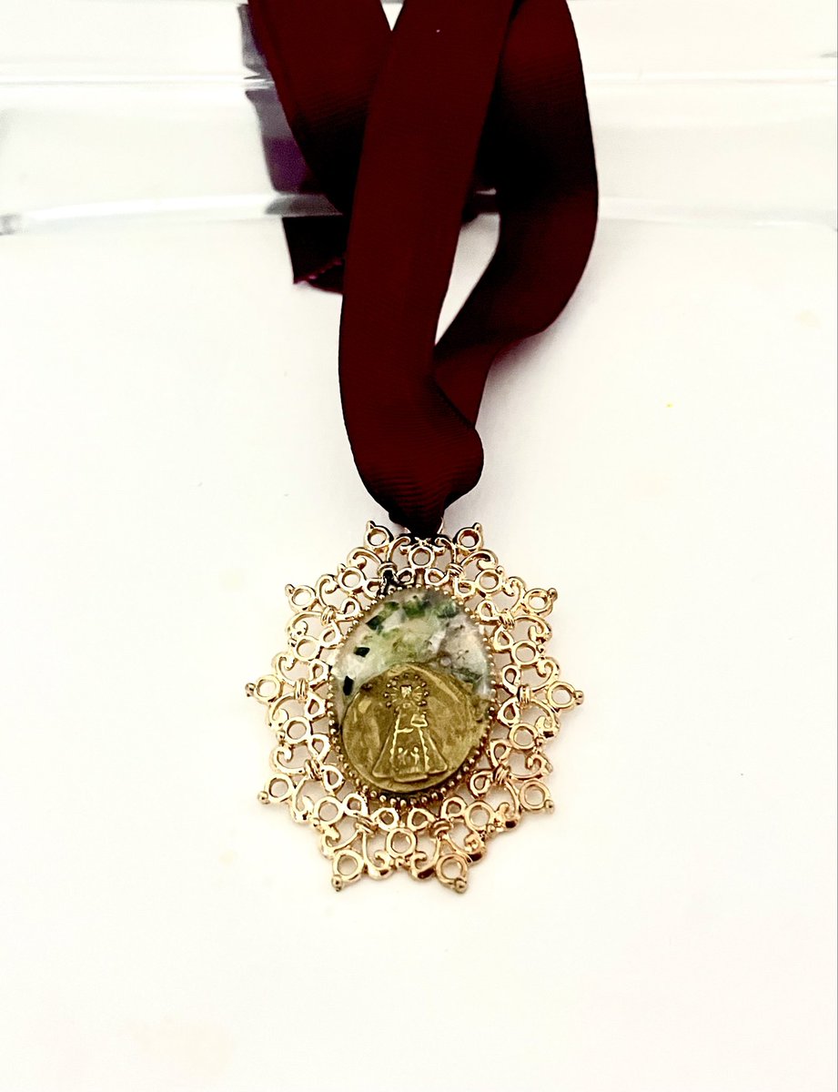 Dos medallas de la Virgen de los Desamparados creadas en escarcha de nácar y presentadas en una elegante cuna dorada. Una pieza que combina delicadeza, brillo y carácter propio, ideal para regalar o para lucir como un detalle especial cargado de significado.